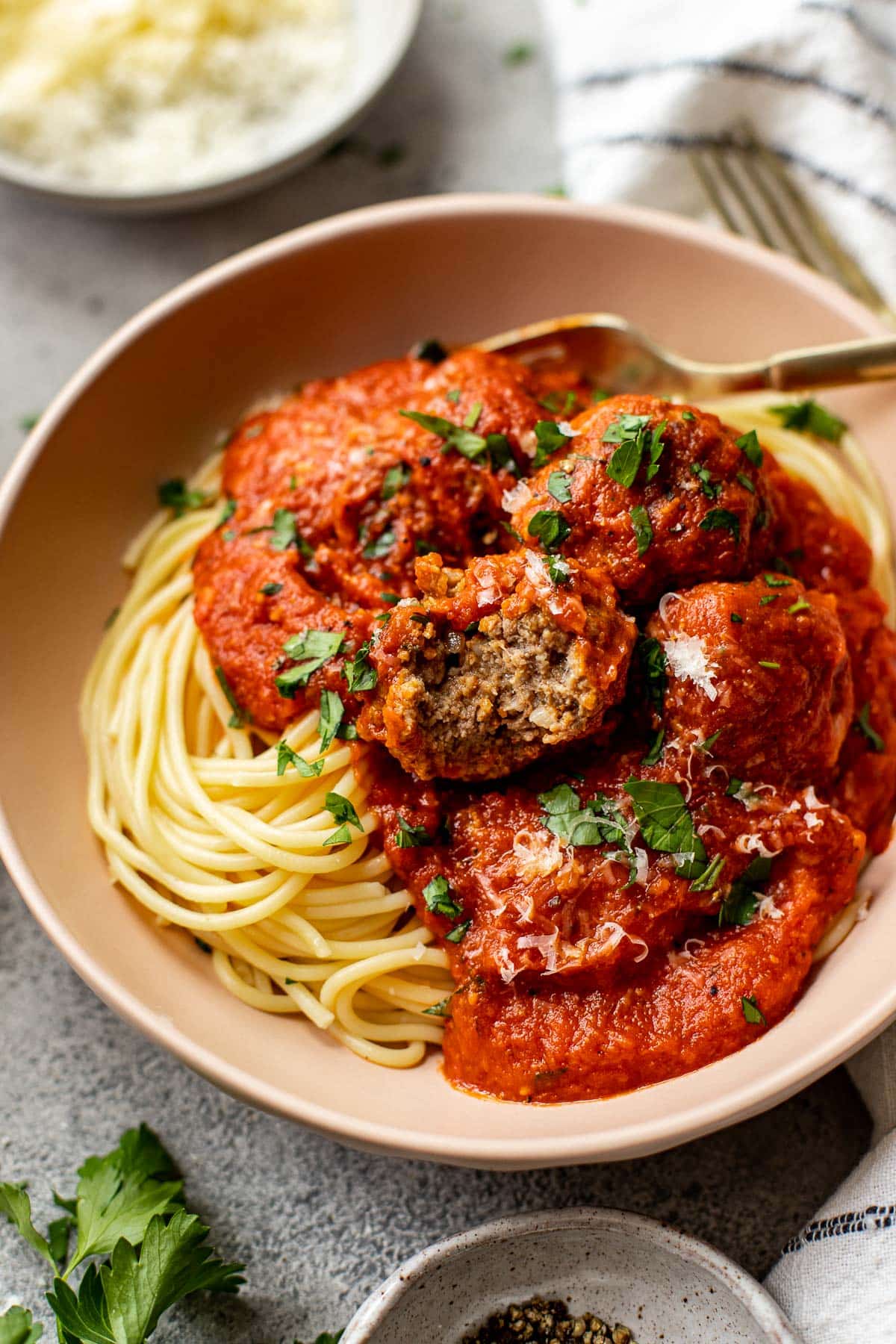 Meatballs and red sauce in a bowl over spaghetti noodles. 