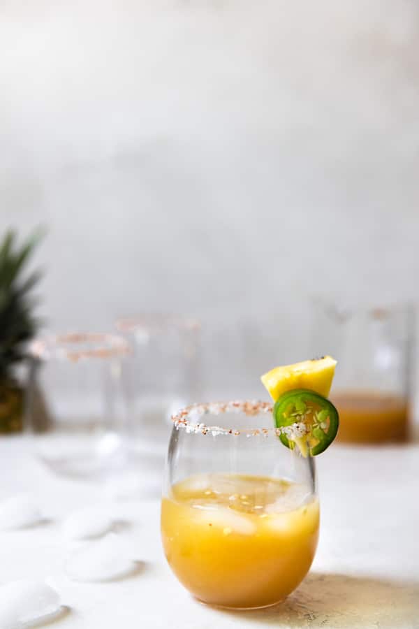 pineapple margarita in a wine glass with a salted rim 