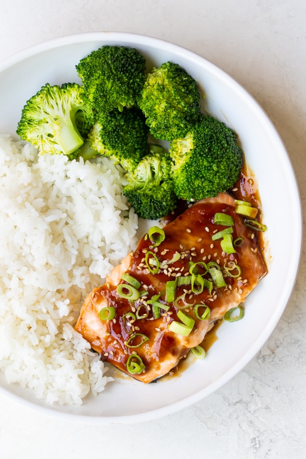 teriyaki glazed salmon in a white bowl with rice and broccoli