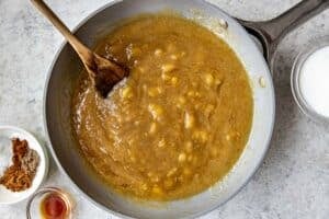 mashed bananas in a saute pan with a wooden spoon.