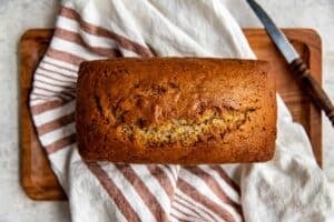 freshly baked rum banana bread on a hand towel on a cutting board.