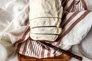 glazed banana bread cut into slices on a cutting board.