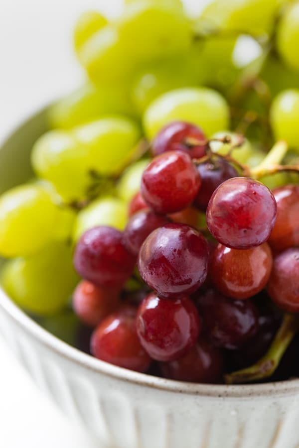 a bowl of red and green grapes