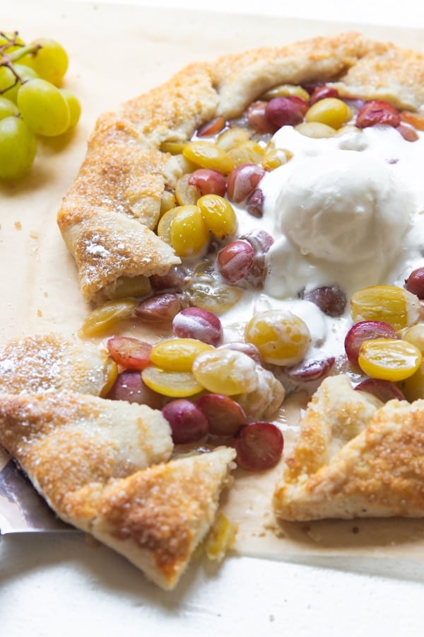 grape galette on parchment paper with ice cream on top