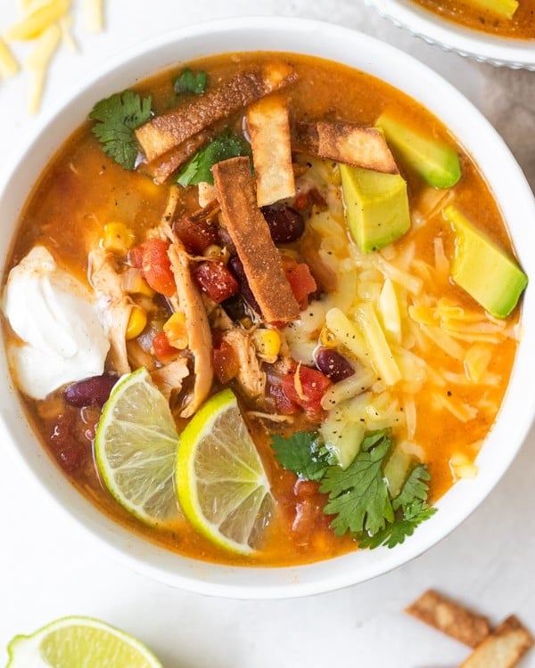 taco soup in a white bowl with toppings on top