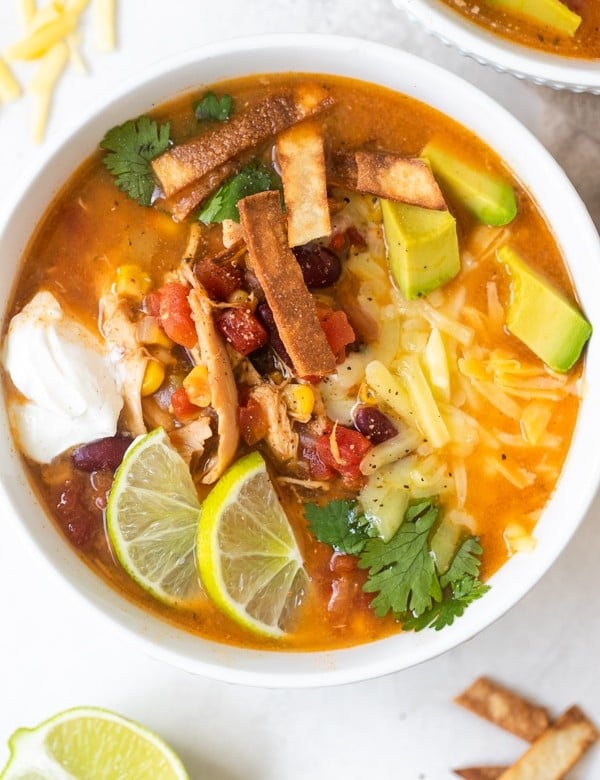 taco soup in a white bowl with toppings on top