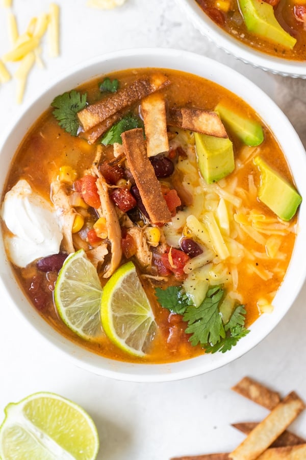 taco soup in a white bowl with toppings on top