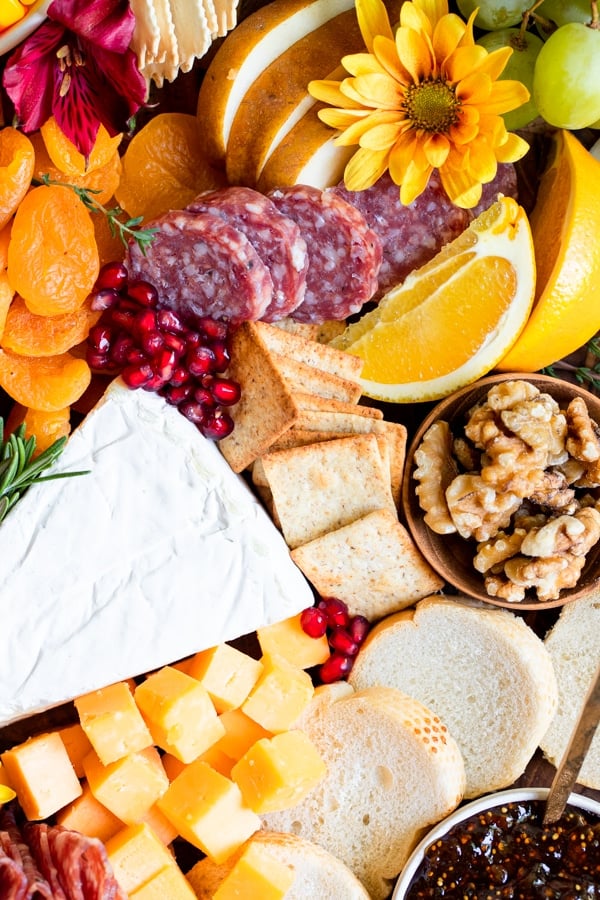 a charcuterie board filled with fruits, meats and cheese on a wood cutting board
