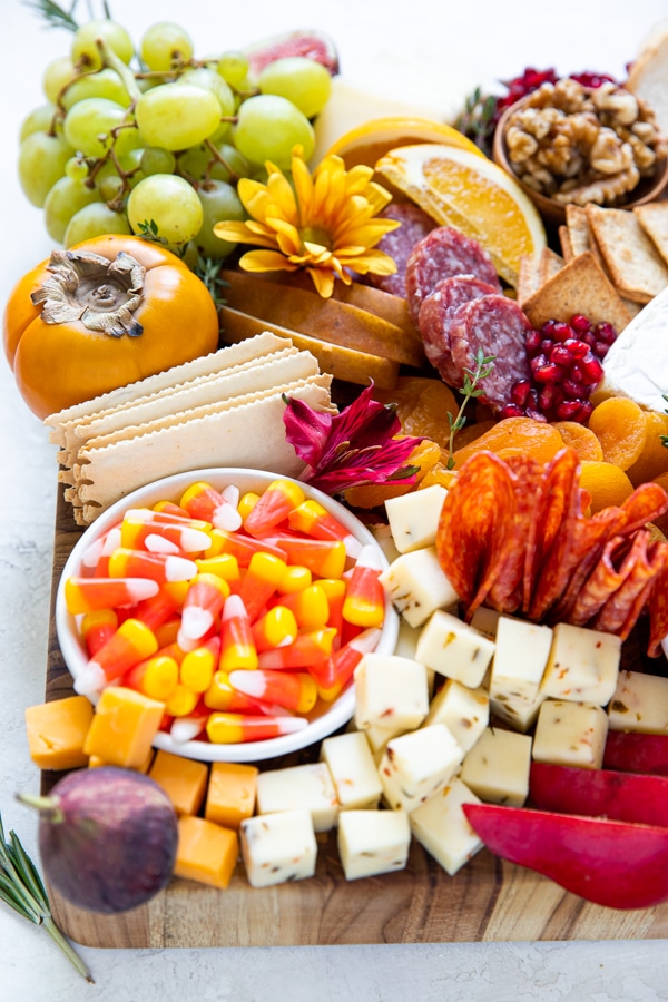 a charcuterie board filled with fruits, meats and cheese on a wood cutting board