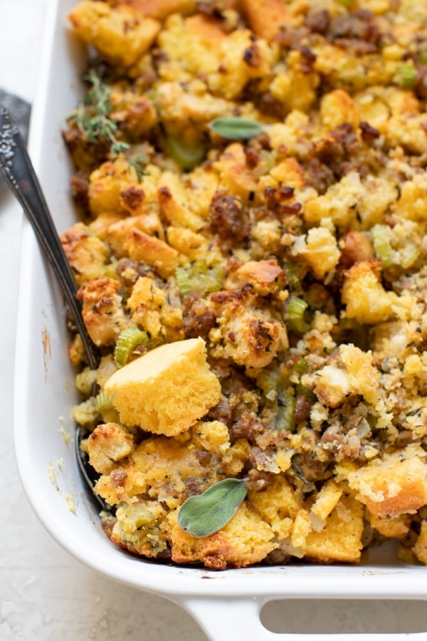 cornbread stuffing made with sausage and herbs in a white casserole dish