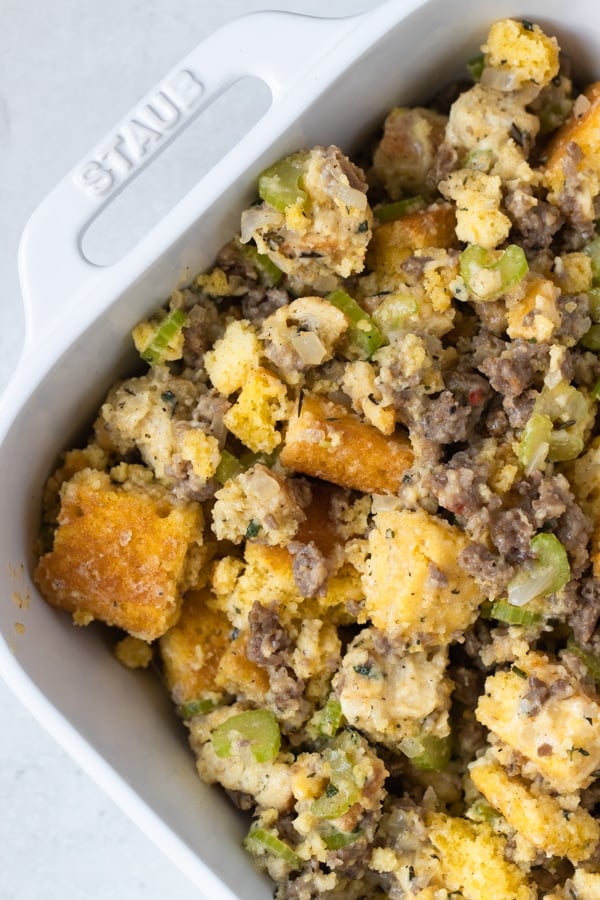 cornbread stuffing made with sausage and herbs in a white casserole dish