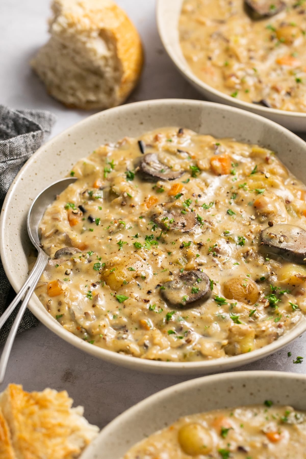 creamy soup in a white speckled bowl with parsley on top.