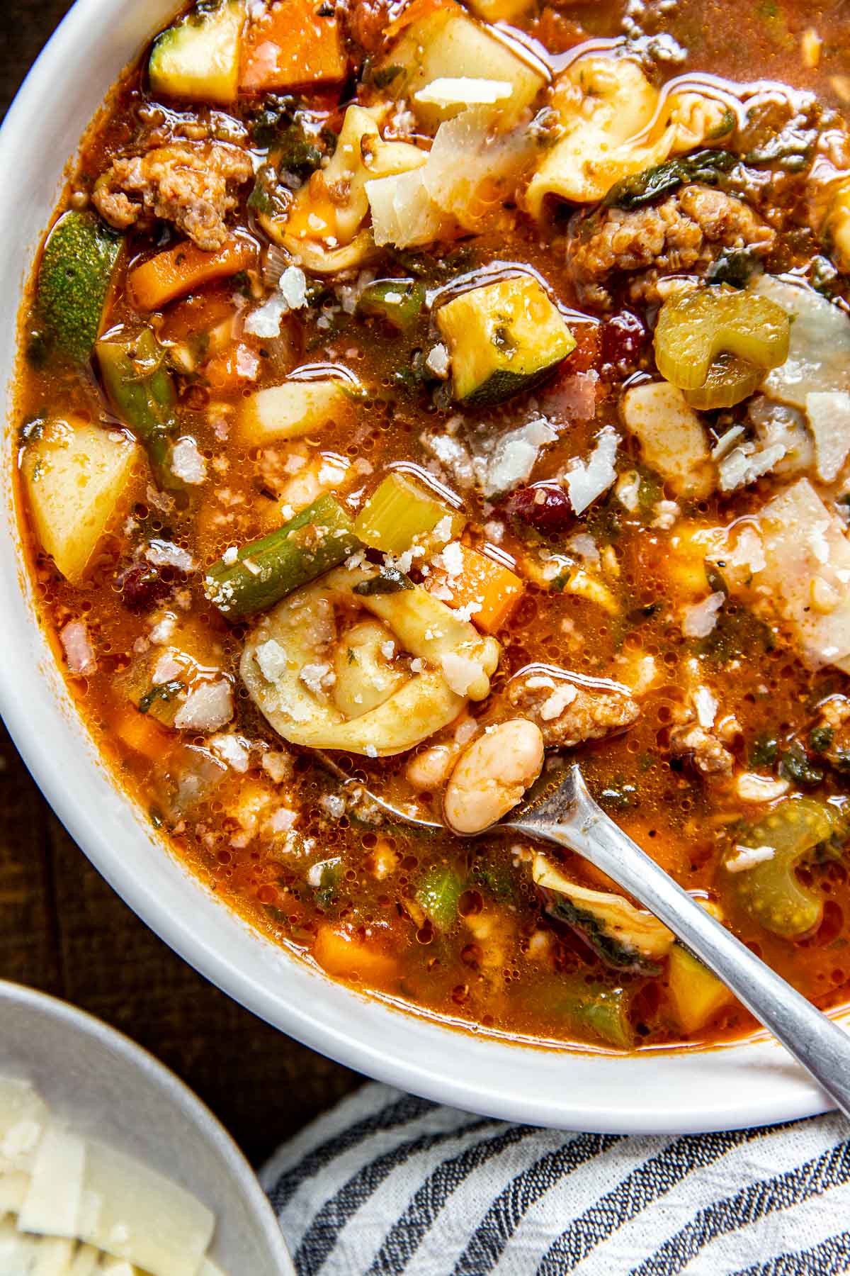 a bowl of minestrone in a large bowl with parmesan on top. 