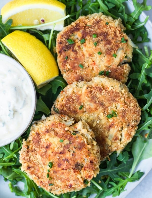 crab cakes on a white plate with arugula