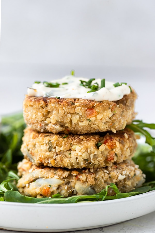 crab cakes with special sauce on a white plate with arugula and