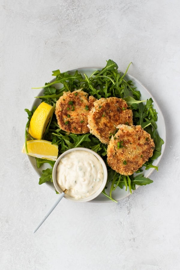 crab cakes on a white plate with arugula 