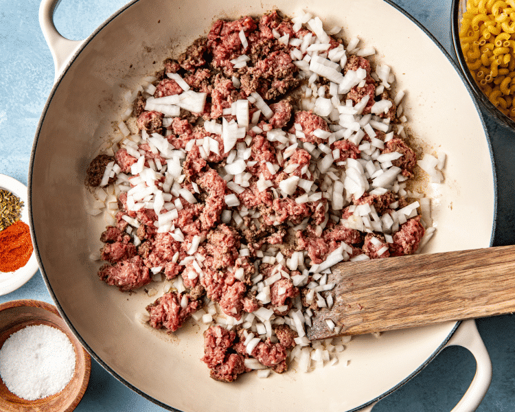 Adding uncooked ground beef and onions to large skillet.