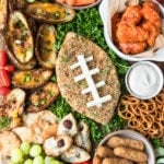 a jalapeno popper cheese ball on a cutting board with game day snack foods