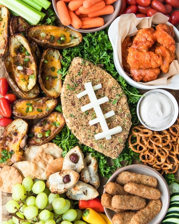 a jalapeno popper cheese ball on a cutting board with game day snack foods