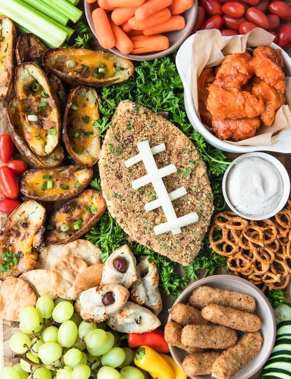 a jalapeno popper cheese ball on a cutting board with game day snack foods