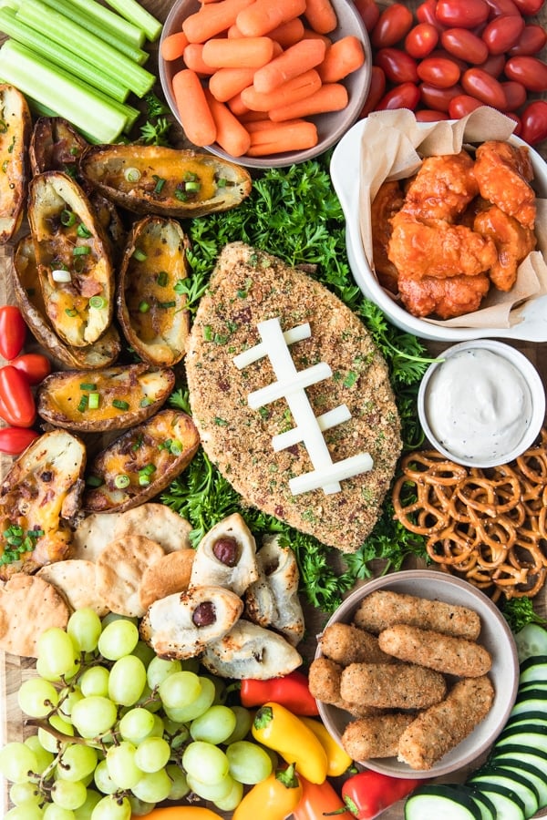 a jalapeno popper cheese ball on a cutting board with game day snack foods
