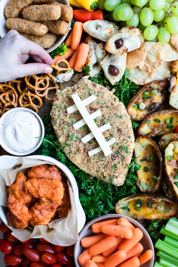 a jalapeno popper cheese ball on a cutting board with game day snack foods