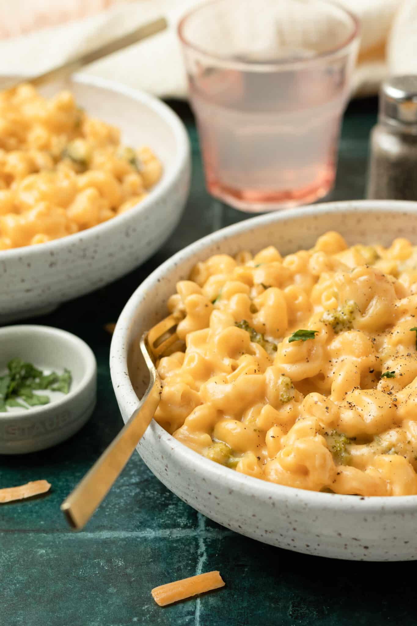 a gold fork in a bowl with macaroni and cheese. 