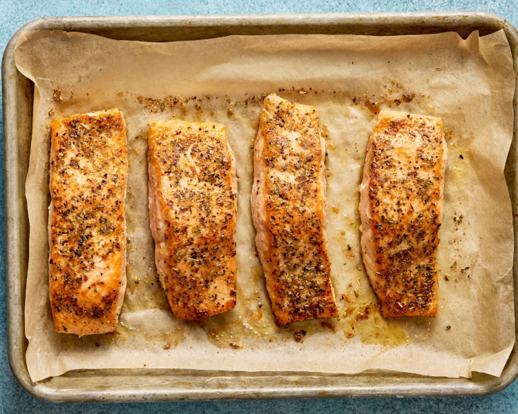 Cooked Mediterranean salmon fillets baked until golden and flaky on a parchment-lined baking sheet.