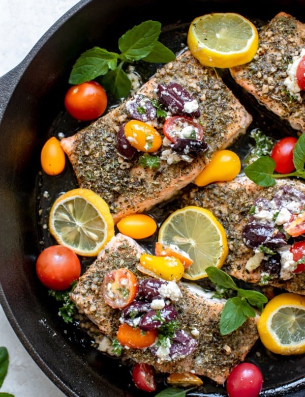 salmon in a cast iron skillet with tomatoes and kalamata olives