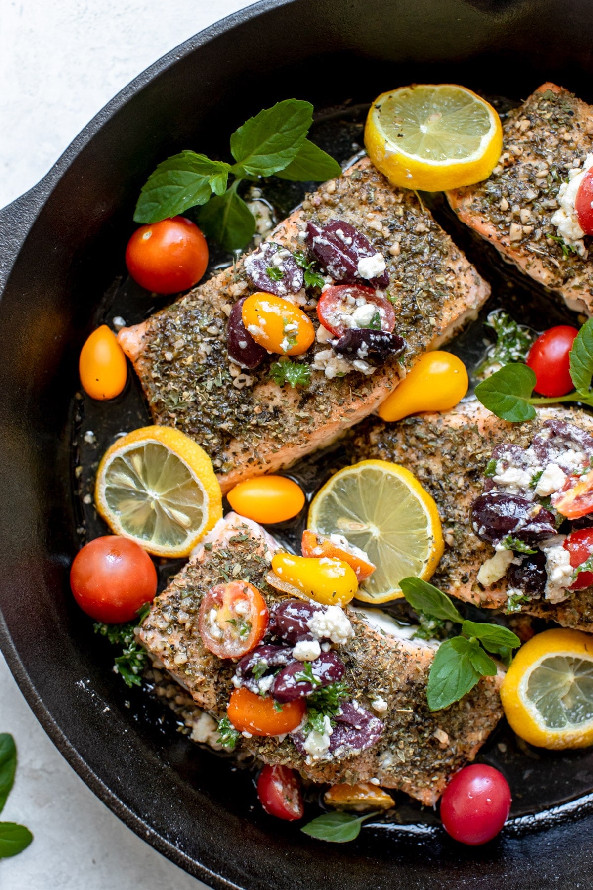 salmon in a cast iron skillet with tomatoes and kalamata olives