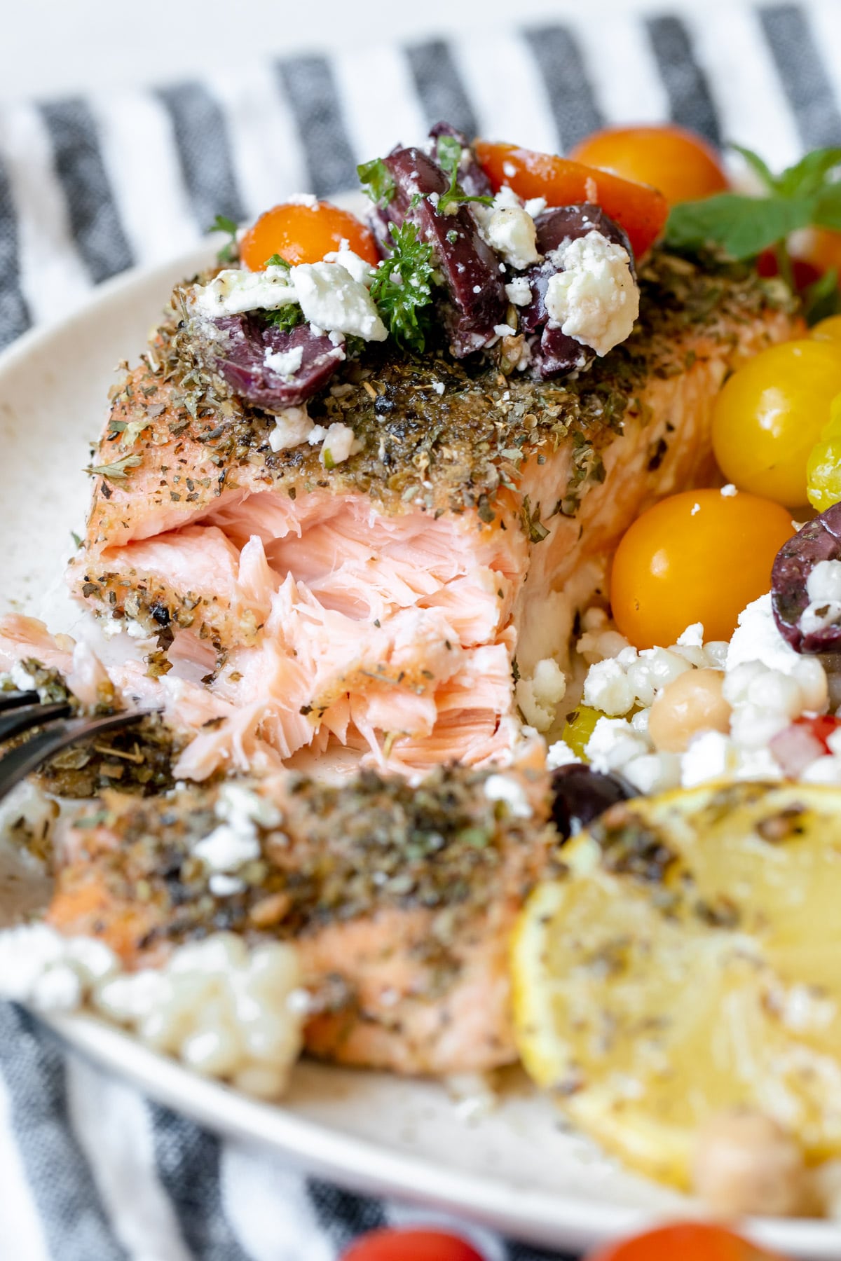a fork flaking off pieces of salmon on a white plate