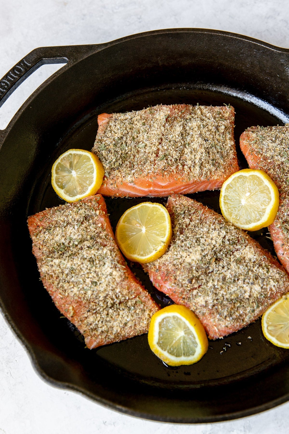 fresh salmon fillets in a cast iron skillet with lemon slices