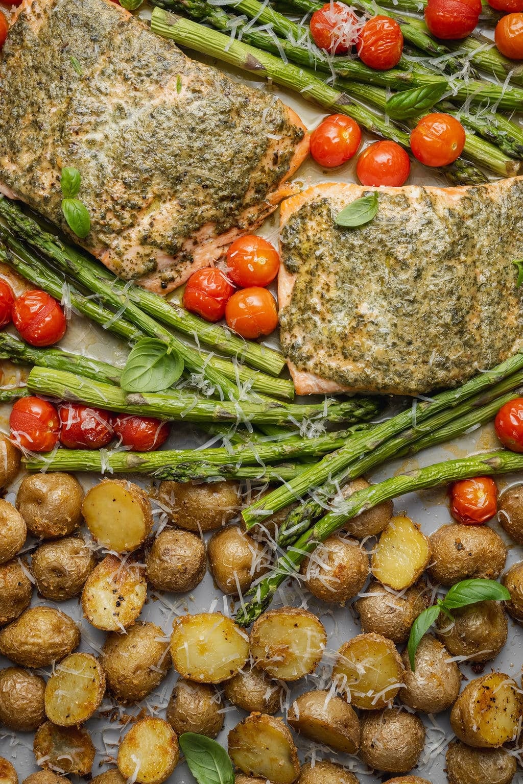 Sheet pan pesto salmon with roasted asparagus, crispy baby Yukon gold potatoes, blistered cherry tomatoes, grated Parmesan cheese, and fresh basil.