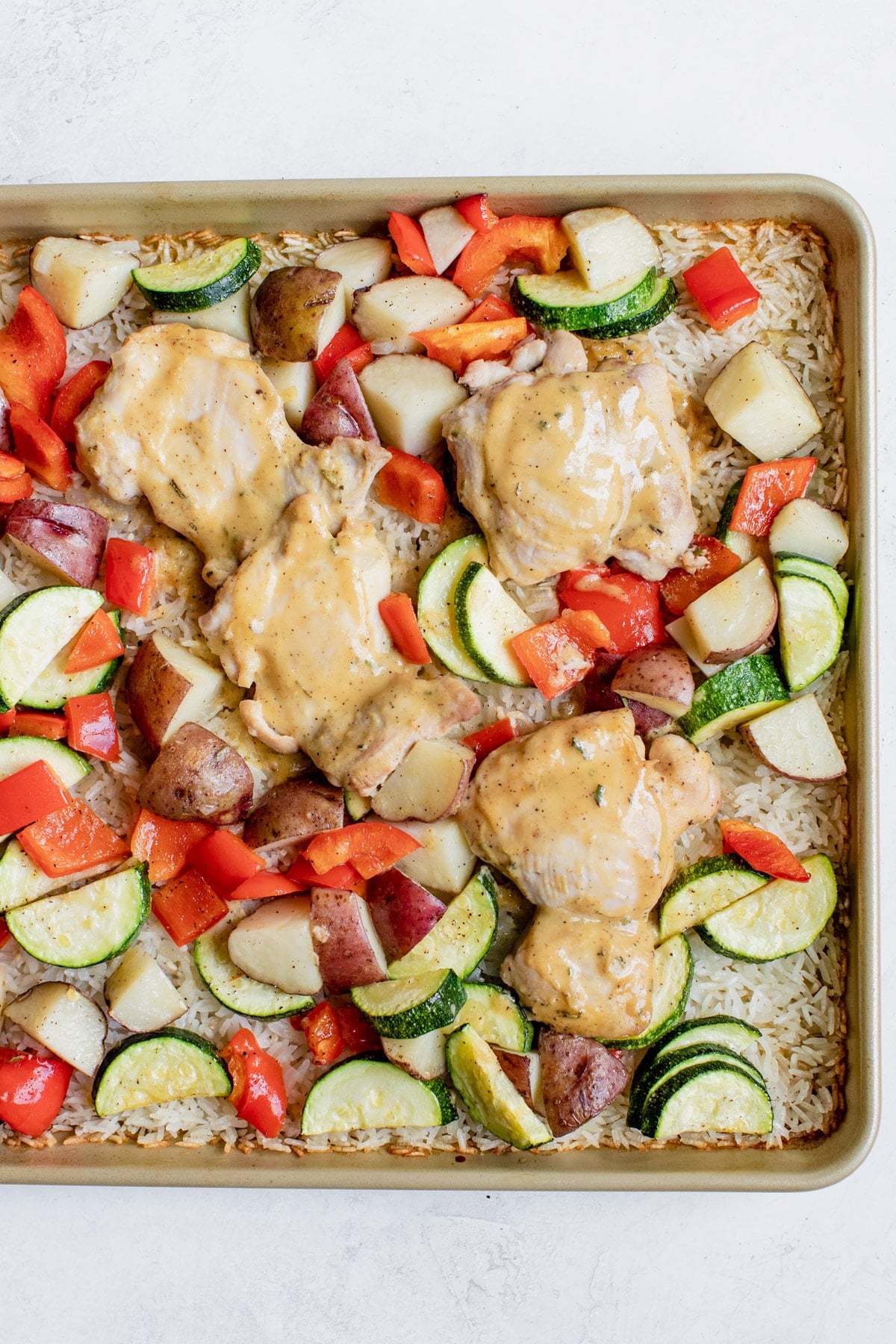chicken and veggies on a sheet pan with rice
