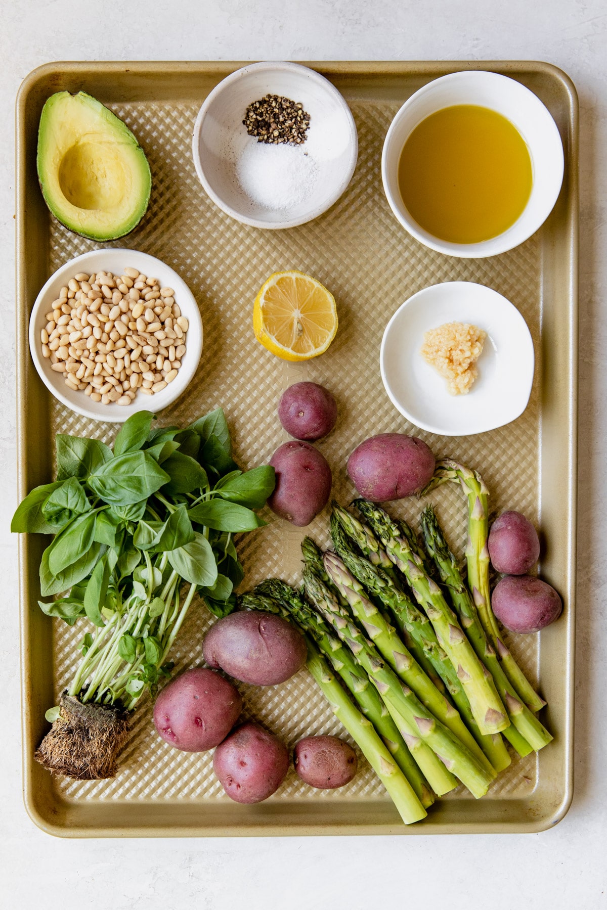 a gold baking sheet with ingredients to make homemade pesto on it