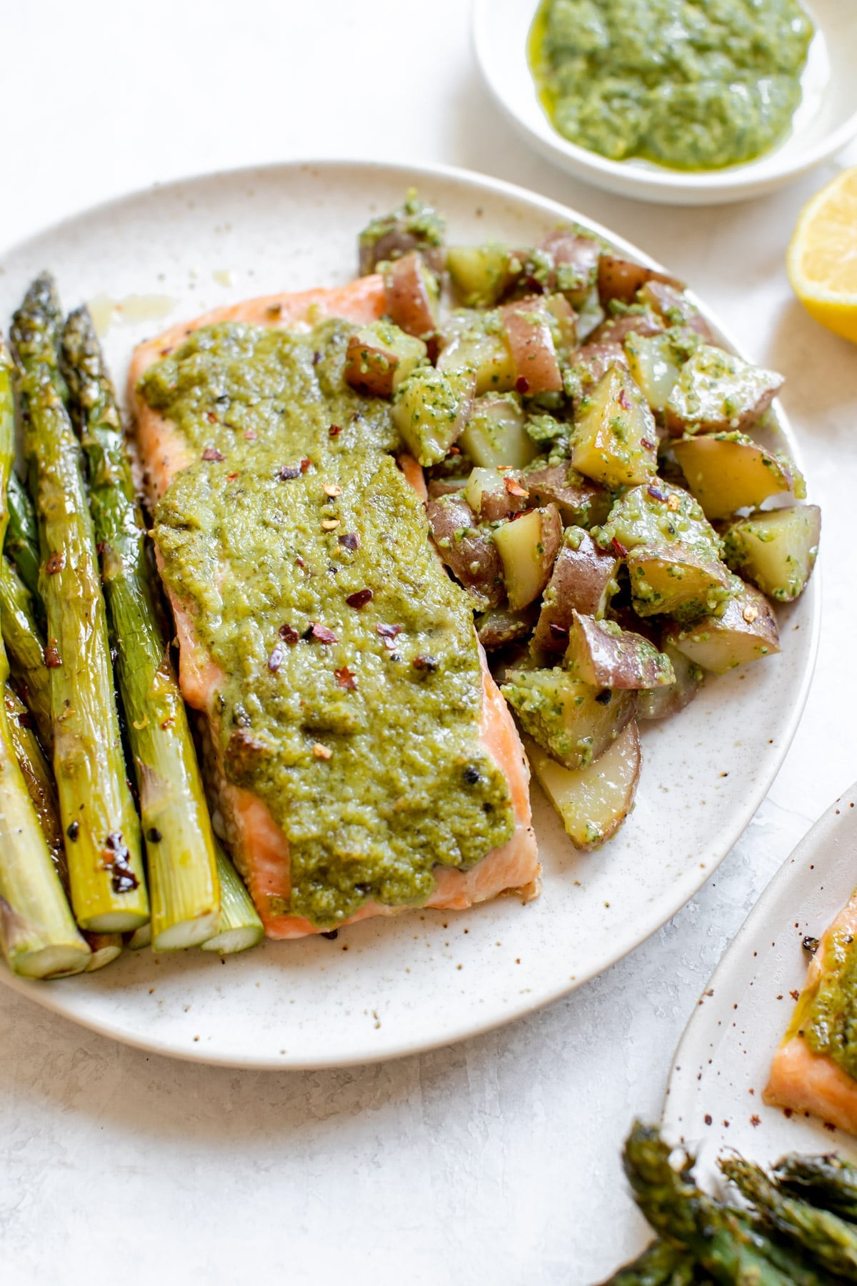 salmon on a white plate with pesto on top