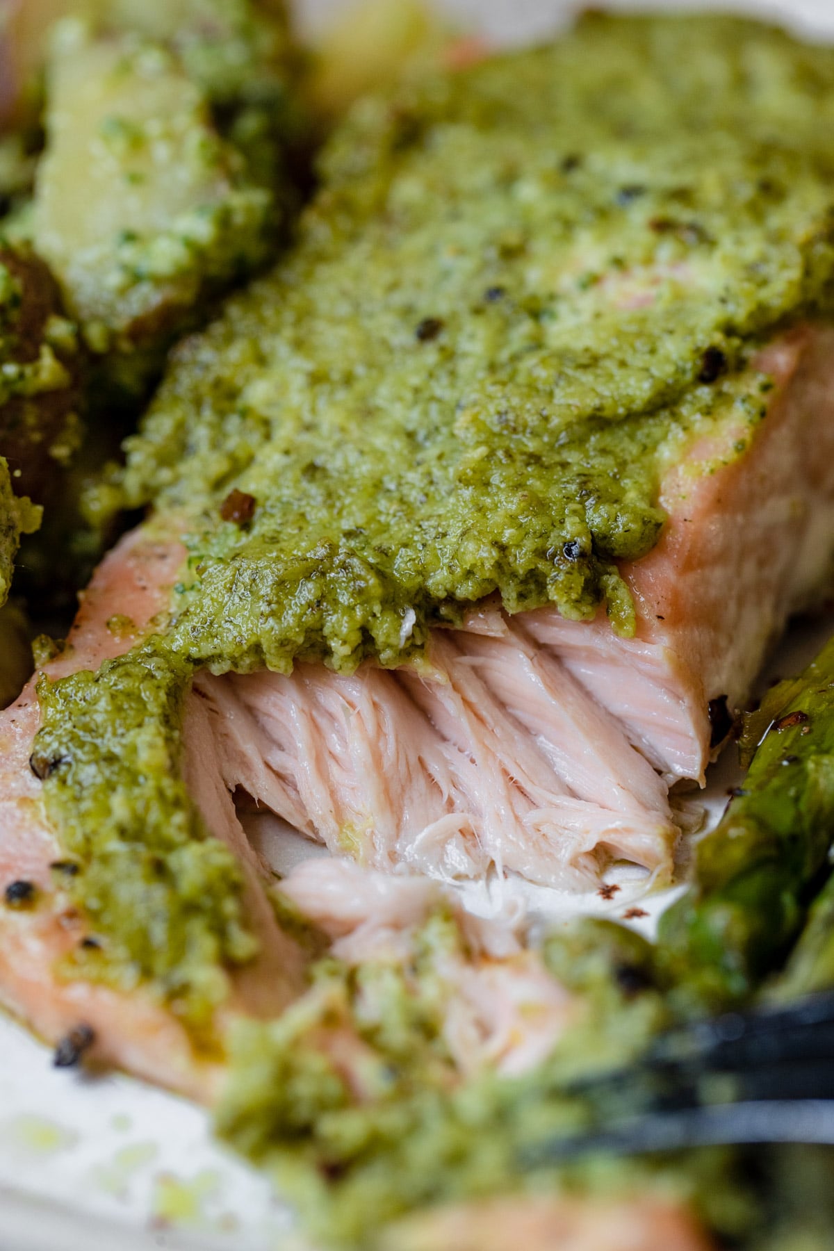 an up close image of salmon topped with a homemade pesto on a sheet pan