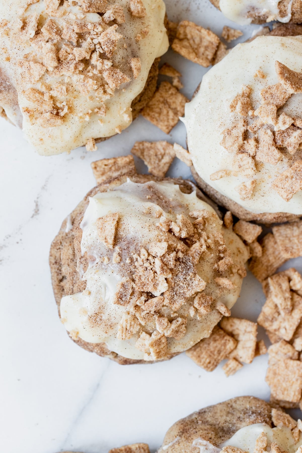 cinnamon toast crunch cookie on a marble slab coated in cream cheese frosting