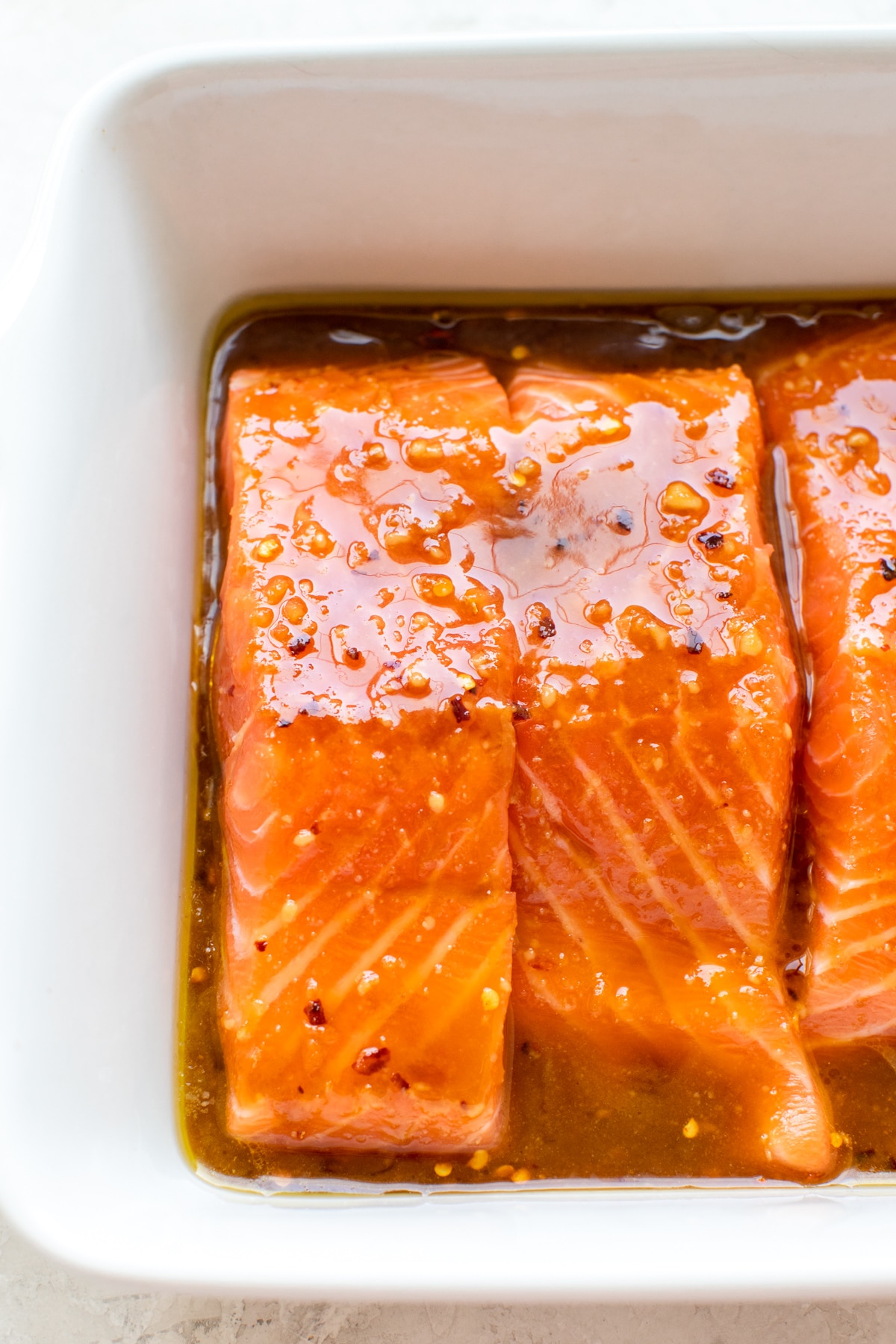 salmon in a white baking dish with a brown sugar glaze poured on top