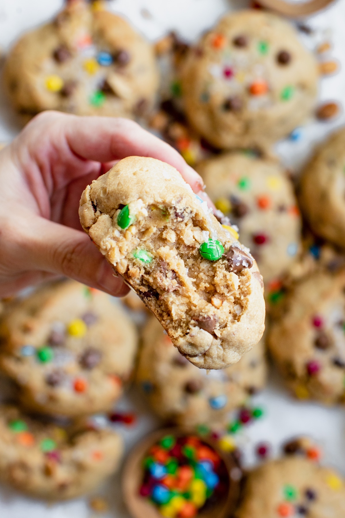 a womans hand holding a peanut butter monster cookie