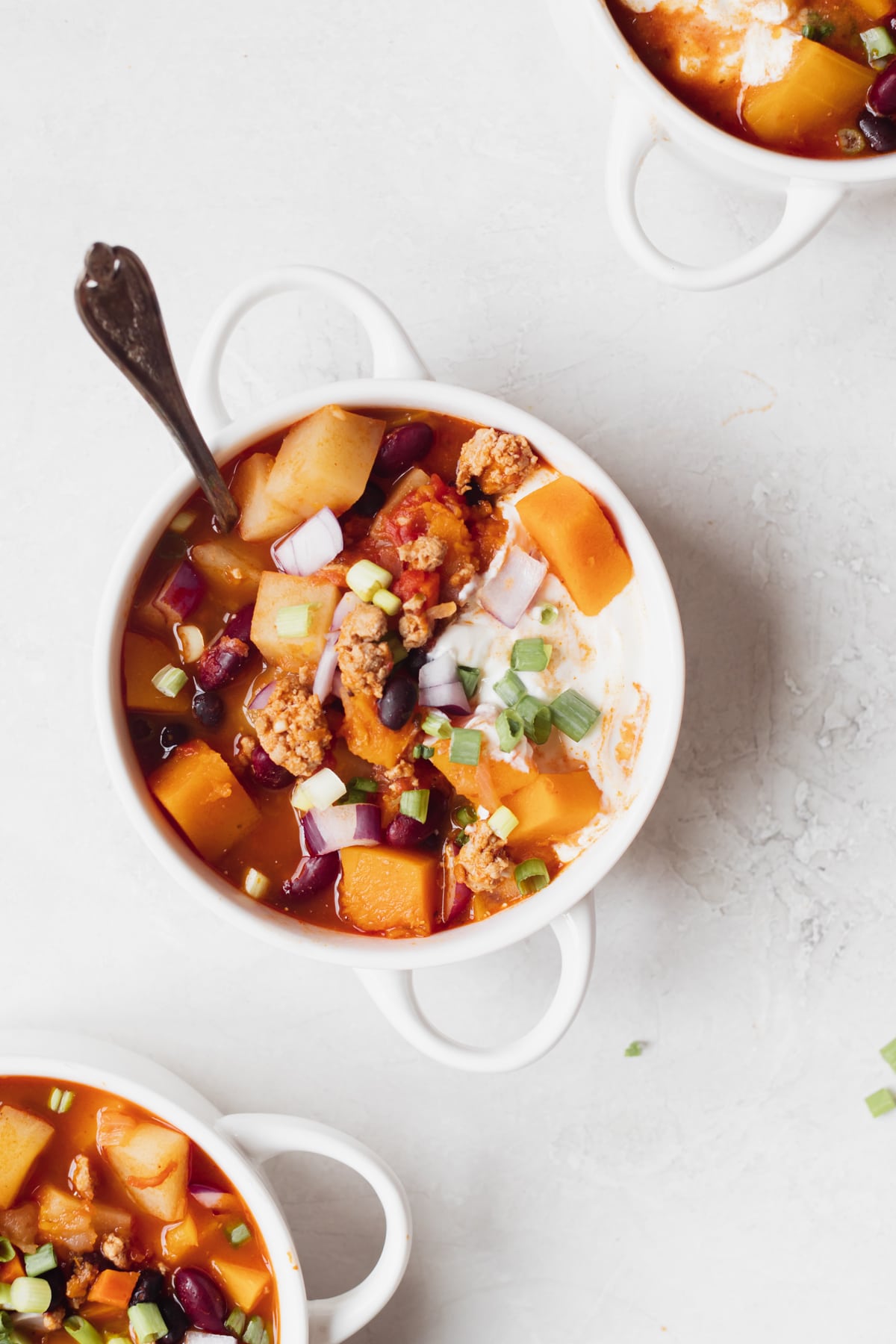 chili in a white soup bowl topped with green onions and sour cream