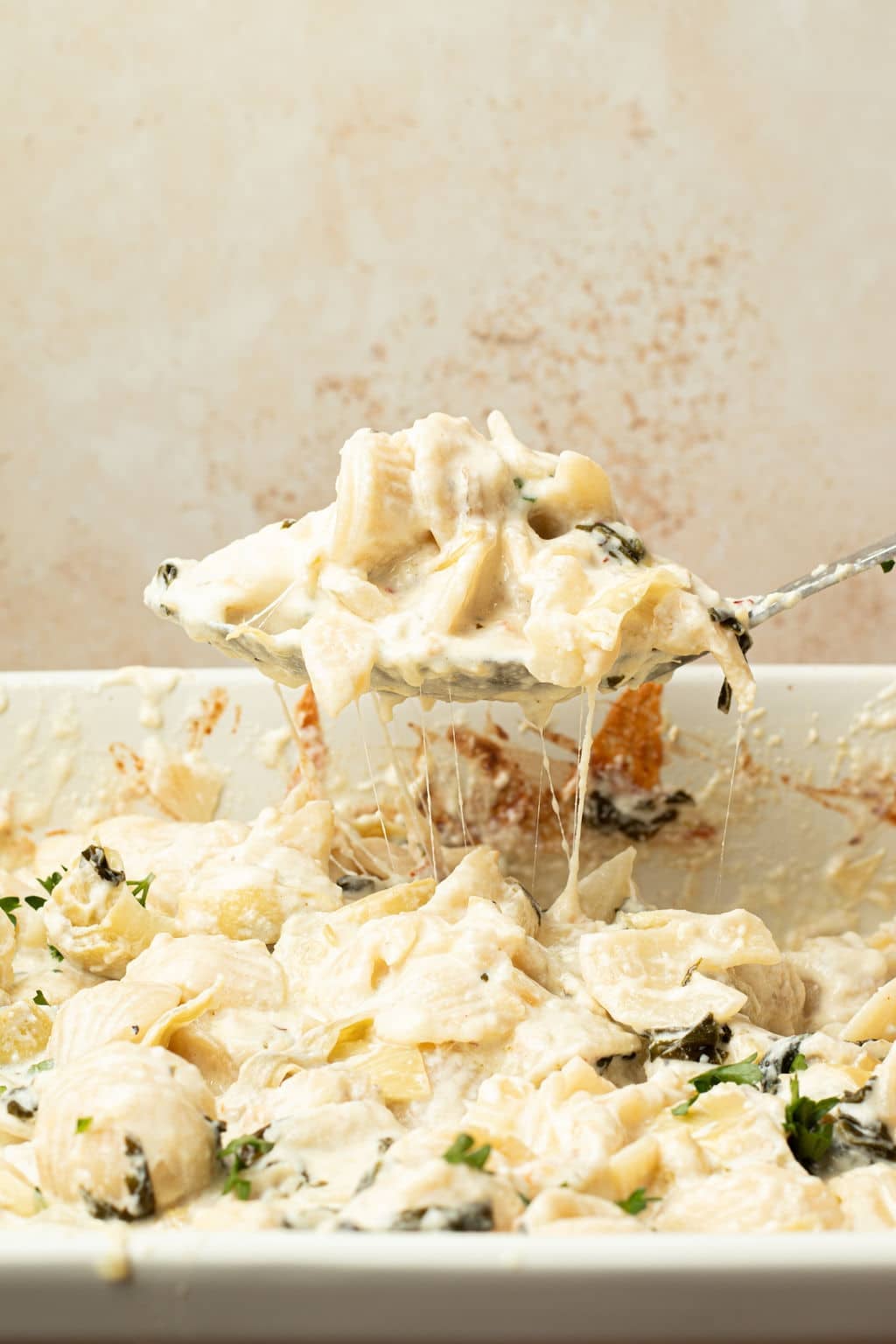 baked spinach artichoke pasta on serving spoon