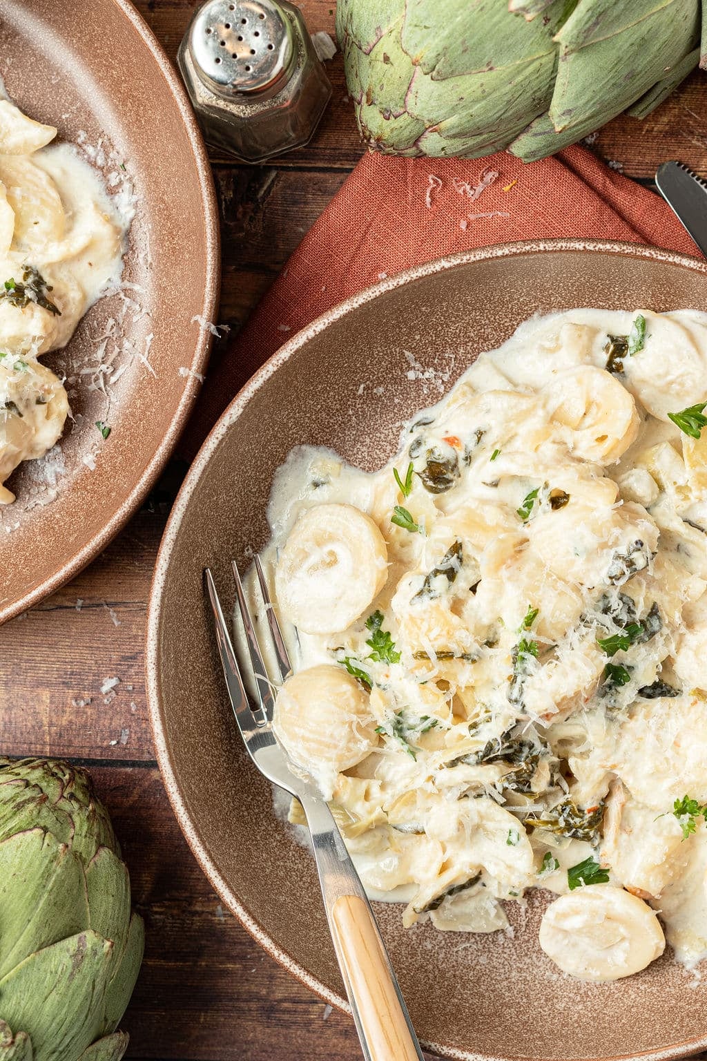 spinach artichoke pasta in bowl with fork