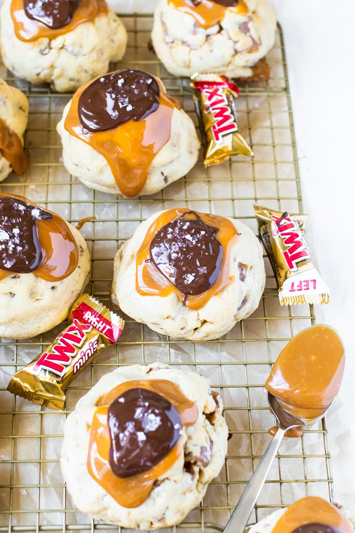 cookies topped with chocolate, caramel and sea salt on a gold cooling rack