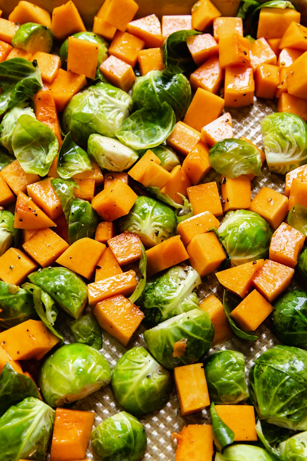 chopped vegetables on a gold sheet pan tossed in olive oil, salt and pepper