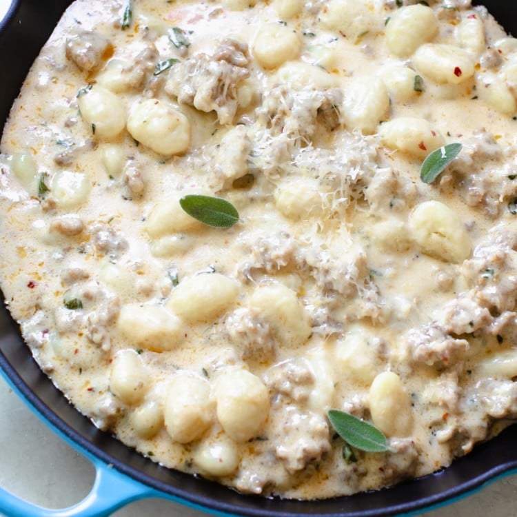 gnocchi and Italian sausage in a cast iron skillet topped with parmesan cheese