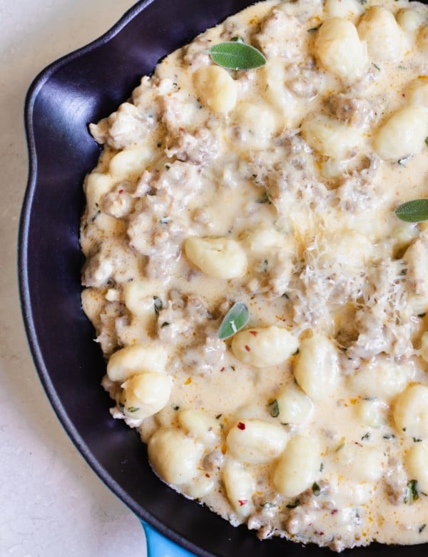 gnocchi and Italian sausage in a cast iron skillet topped with parmesan cheese
