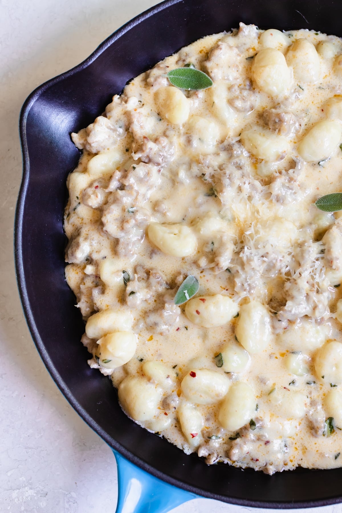 gnocchi and Italian sausage in a cast iron skillet topped with parmesan cheese
