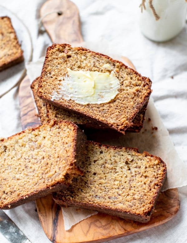 banana bread on a cutting board with butter smeared on top of one slice