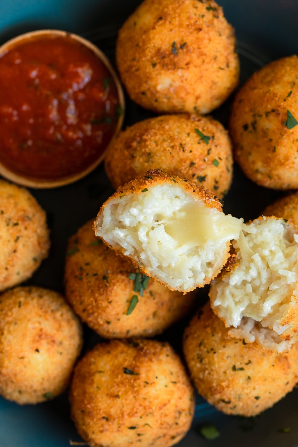 fried rice formed into balls on a blue plate with marinara
